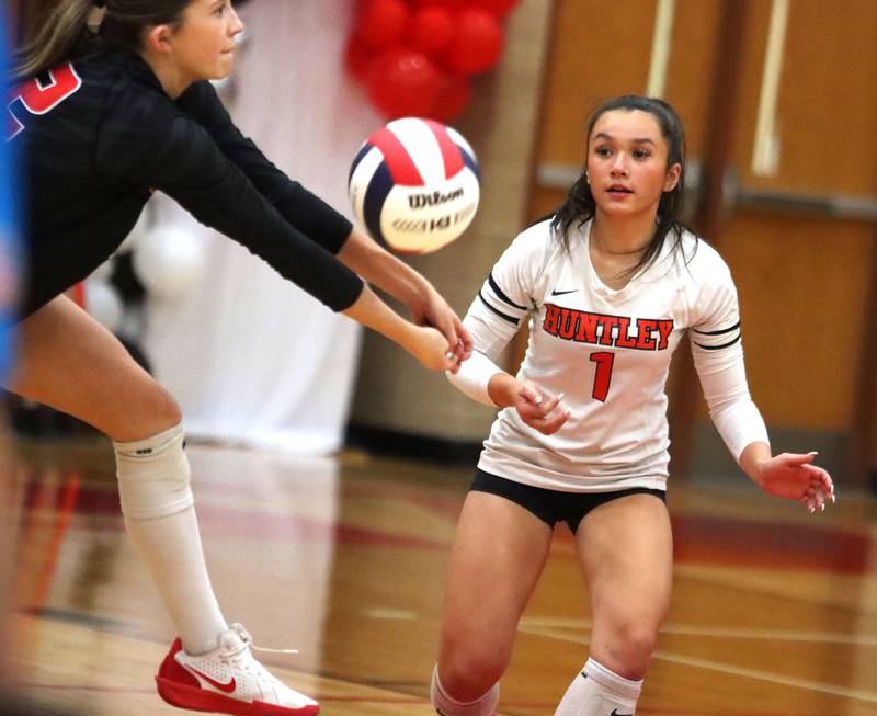 Huntley’s Izzy Whitehouse, left, passes the ball as teammate Sophia Tocmo keeps an eye on the action against  Hampshire in girls varsity volleyball at Huntley High School on Thursday, October 23, 2025.