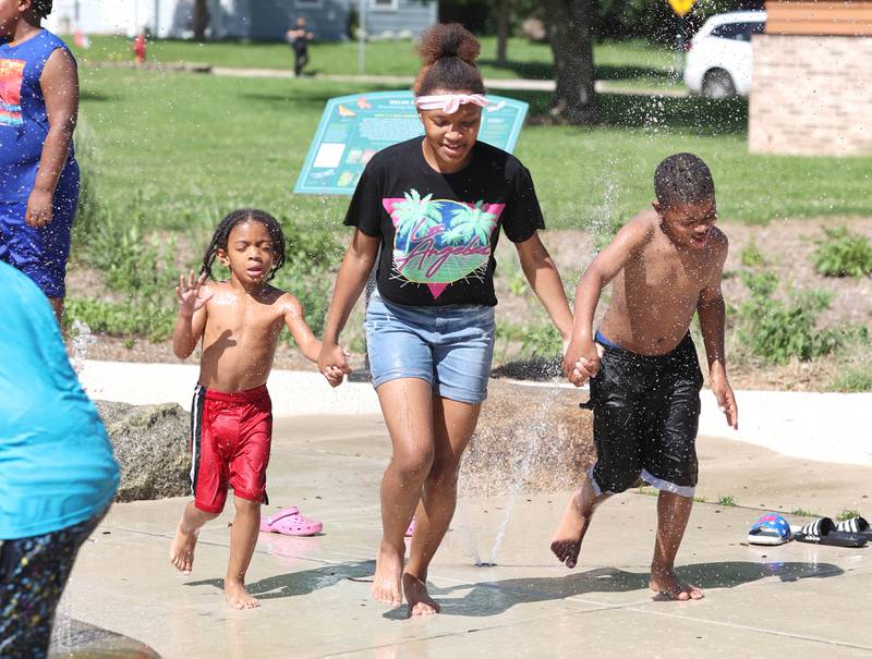 Cammari Pettis, (left) 4, from DeKalb, runs through the sprinklers with his cousins Nuria Ford, 14, and Niree Ford, 8, visiting from Decatur, Tuesday, June 14, 2022, in the splash pad at Welsh Park in DeKalb. Temperatures reached nearly 100 degrees Tuesday and highs are expected to remain in the 90's through Thursday.
