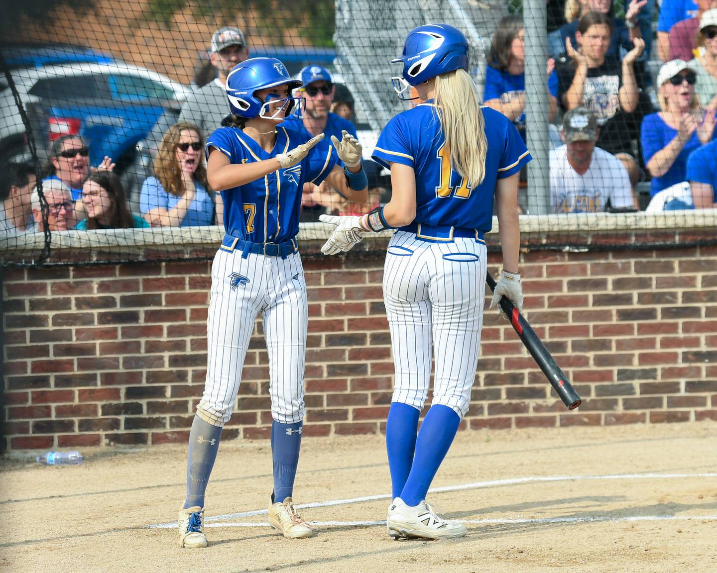 Wheaton North's Hana Stoner (7) gets congratulated by teammate Makayla Hammer (11) after Hana scores a run during the sectional semifinal game on Thursday June 5, 2025, while taking on Weaton Warrenville South held at Oswego High School.