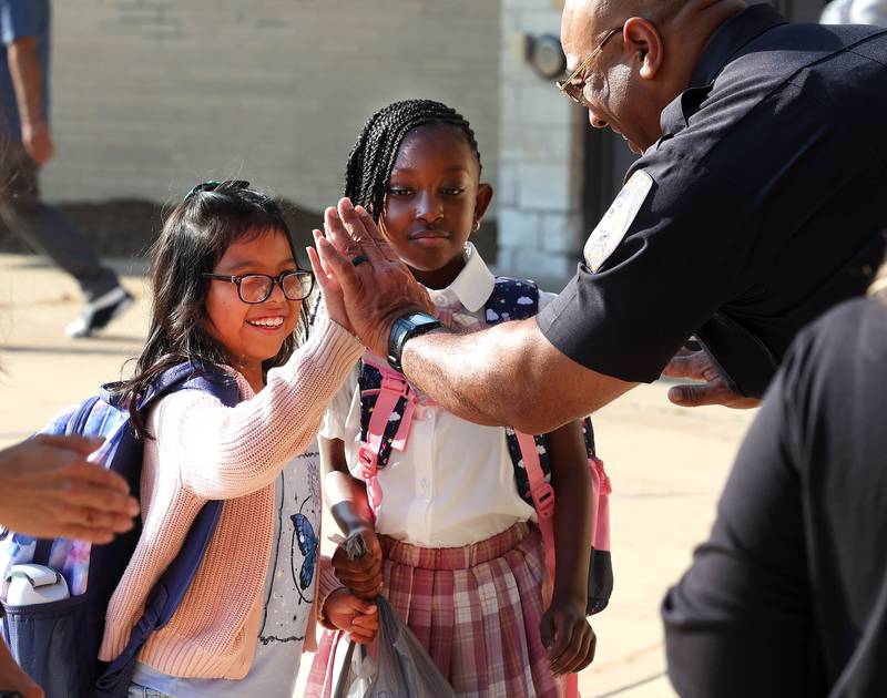 DeKalb Police Chief David Byrd high fives students Wednesday, Aug. 13, 2025, as they arrive for the first day of school at Founders Elementary in DeKalb.