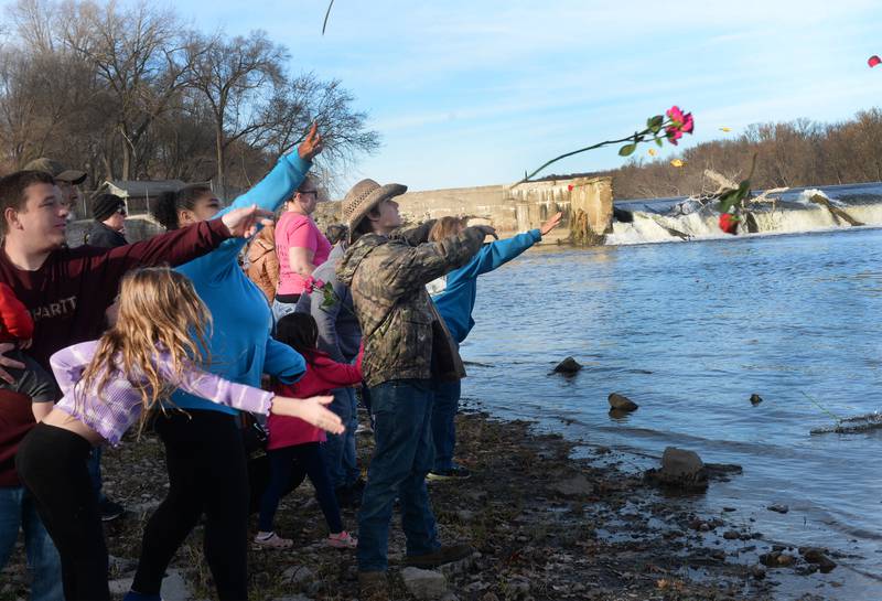 Family and friends of Kent "Bud" Dearborn Jr., throw flowers into the Rock River on Sunday, Nov. 19, 2023 in commemoration of Dearborn's boating accident in 2019 that claimed his life and a fishing companion below the Oregon dam. Dearborn's body has not been found.