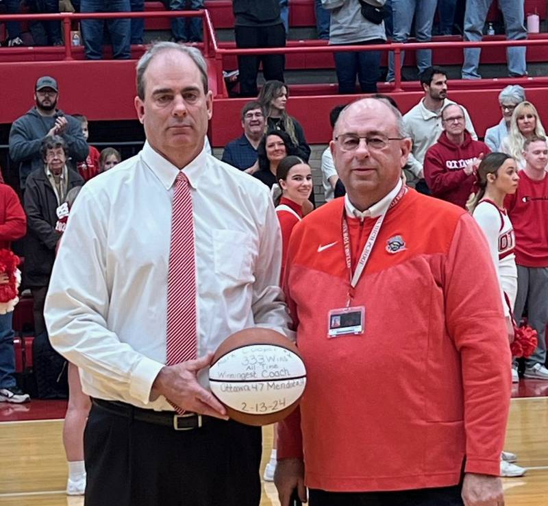 Ottawa boys basketball coach Mark Cooper (left) accepts a commemorative ball for becoming the program's all-time win leader from his brother and OHS athletic director Mike Cooper prior to the Pirates' Feb. 16 game against La Salle-Peru.