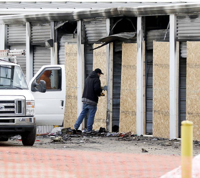 A worker installs chipboard on a storage unit at Life Storage, 2301 W. Algonquin Road, Algonquin, on Monday, Feb. 6, 2024, after a fire the day before. An estimated 25 to 35 storage units were damaged or destroyed, up from the initial estimate of 20.