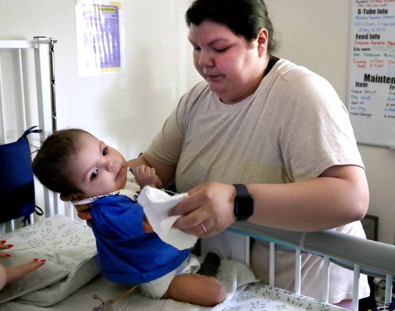 Kassandra Santos works with her daughter Marely, 1, Monday, June 30, 2025, at their home in DeKalb. Marely was born with a myriad of health issues that require around-the-clock care and recently received a heart transplant.