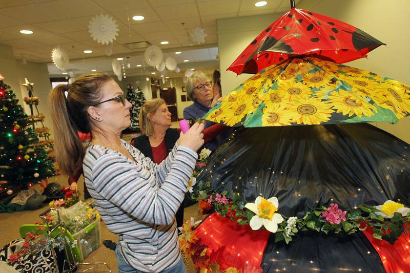 Cheryl Lettow, of Round Lake Beach, on Nov. 19 works with Nancy Musselman and Carol Wegner, both of Grayslake, stapling leaves and flowers on umbrellas for the Grayslake Greenery Garden Club tree that will be on display for the Giving Trees exhibit at the Grayslake Heritage Center & Museum. The Giving Trees will be on display through the holidays.