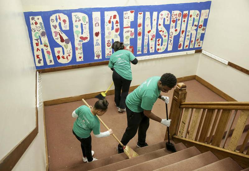 A group of volunteers sweep the main stairwell of the Joliet Boys and Girls Club on Saturday during an expansive overall and remodeling of the organization's building in Joliet.