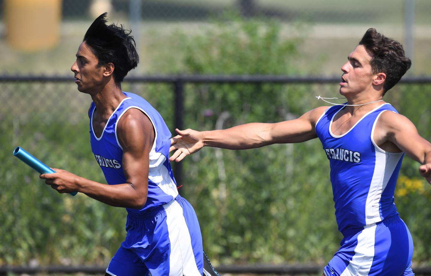 St. Francis lead off runner Gabe Siracusano gives a helping push to teammate Aakash Martin after handing the baton in the 4x100-meter relay at a Class 2A boys track sectional meet in Glen Ellyn on Thursday, June 10, 2021.