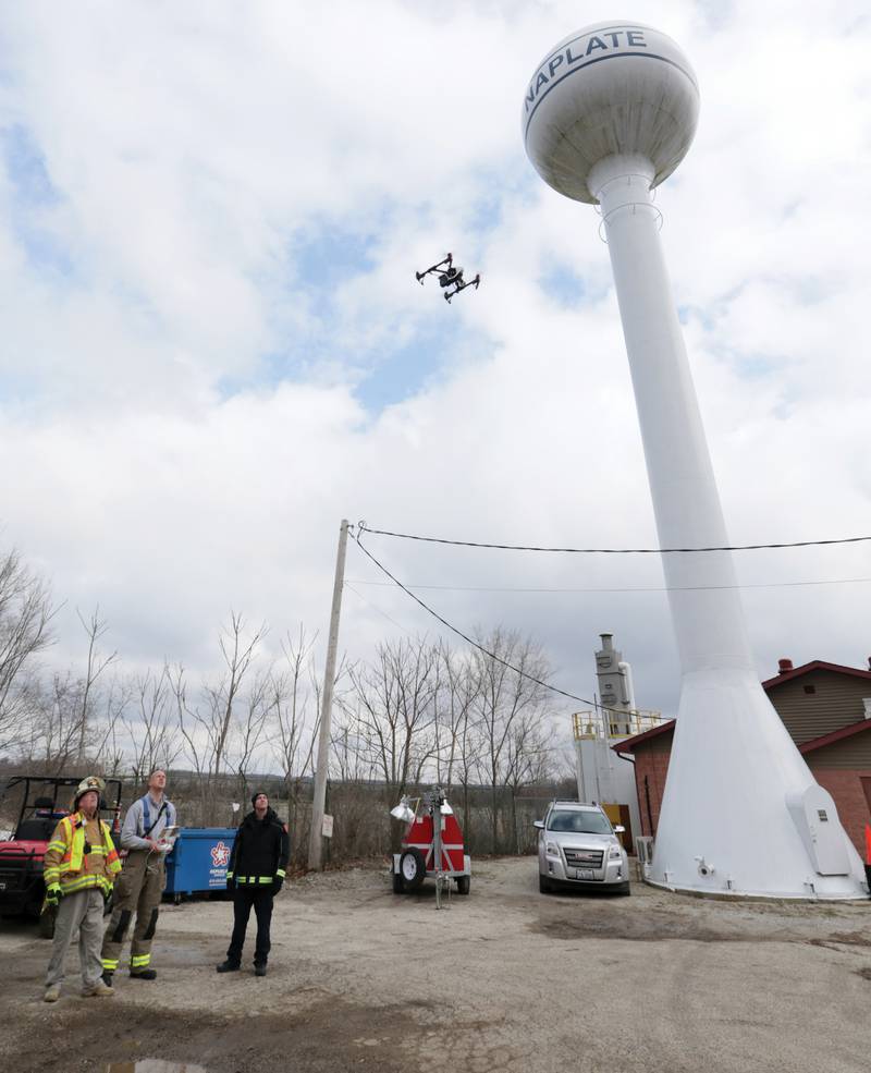 (From left) Ed Rodgers, Utica assistant fire chief, Bryan Park, Streator lieutenant firefighter and Jeff Arendell launch a drone underneath the Naplate water tower on Thursday. New drone technology allows the firefighters collect specialized data and assess the EF-3 tornado damage that hit the town on Wednesday, March 1 2017 in Naplate.