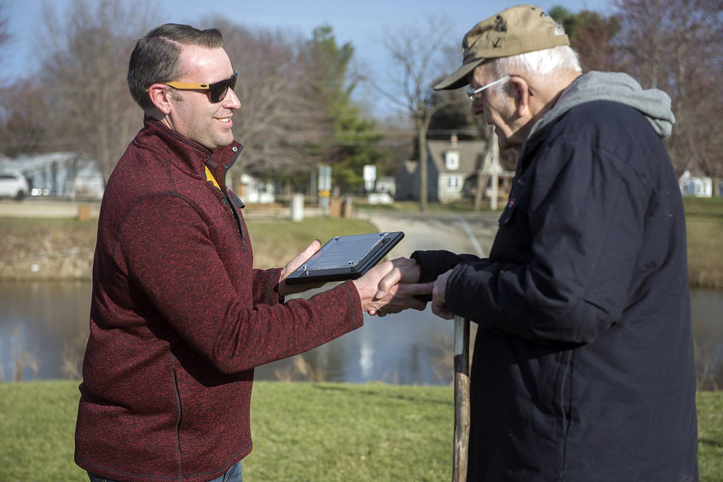 Kyle Sommers, RRDA president, hands Keller his lifetime achievement award plaque. The ceremony was held at a natural grass area at the mouth the Hennepin Canal.
