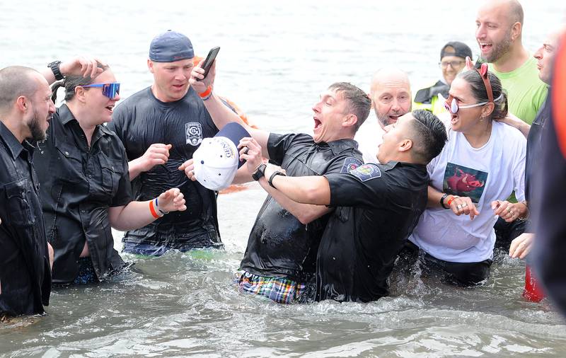 Despite the cell phone, Geneva Sgt. Brad Jerdee gets pulled into the water by Ofc. Emigdio Garcia during the annual Polar Plunge to support Special Olympics Illinois at Siver Springs State Park's Loon Lake on Sunday, Mar. 5, 2023.