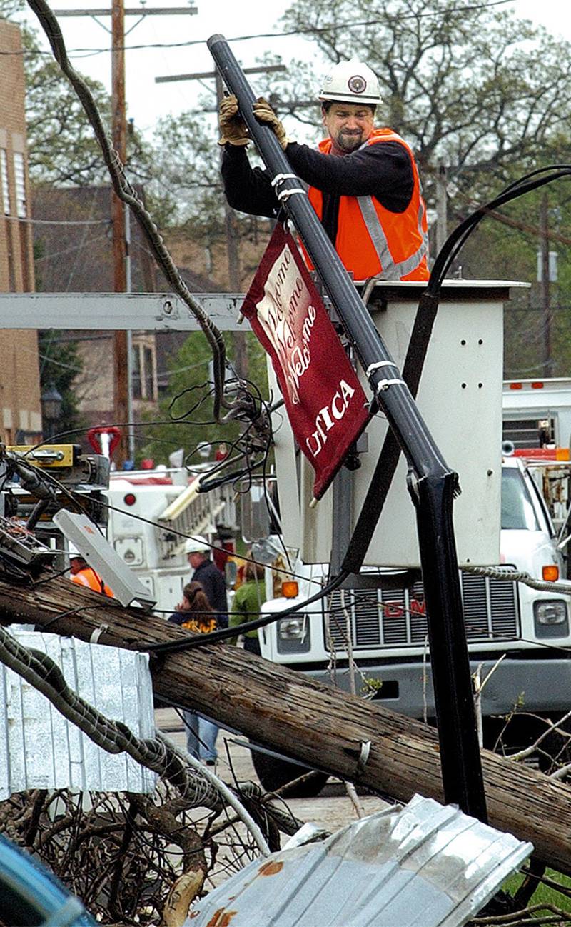 A worker dismantles a light pole holding a Utica banner during the aftermath of the tornado that hit Utica on April 20, 2004.