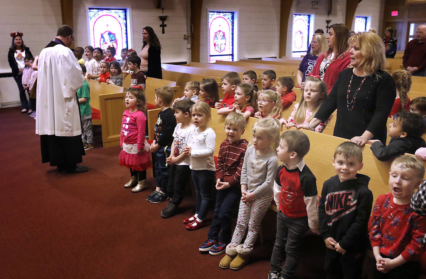 Students pray with Rev. Mark Buetow, of the Zion Evangelical Lutheran Church in McHenry, on Wednesday, Feb, 14, 2024, during chapel for the students from the church’s school and church members on Ash Wednesday.