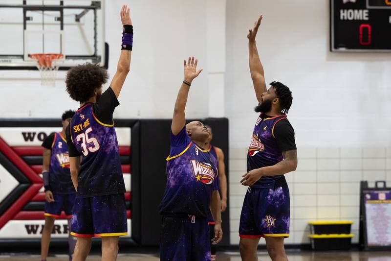 Tyler “Sky-Rise” Cronk (35) and Deven “Just Do It” Dorsett (10) of the Harlem Wizards raise hand whilst teammate Arnold “A-Train” Bernard (9) attempts to high-five them on Wednesday, April 16, 2025 at Woodland High School in Streator.
