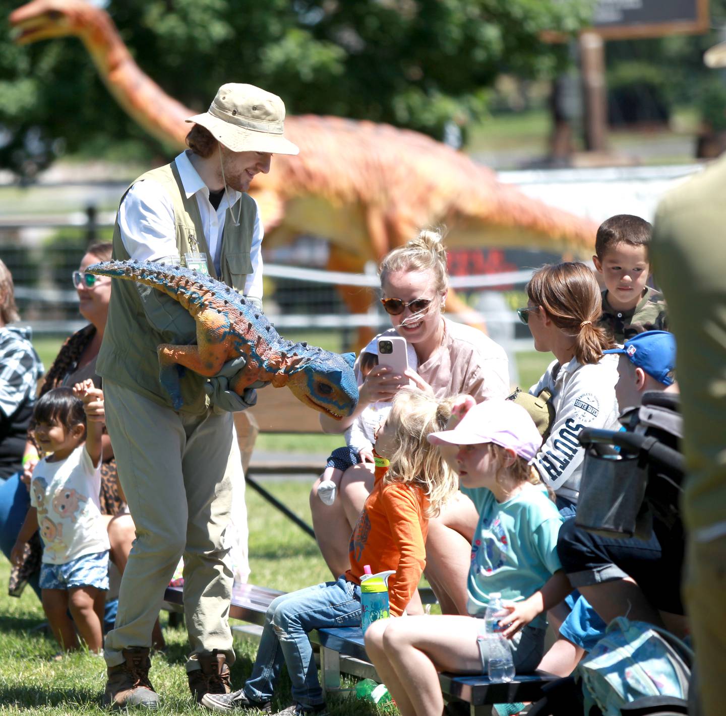 Ashton Cox carries a baby dinosaur during a dinosaur training session as part of the Dino Farm Adventure at Kuipers Family Farm in Maple Park on Thursday, May 30, 2024. The Dino Farm Adventure will be at Kuipers until June 16.