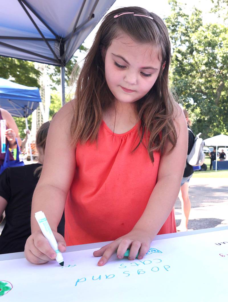 Abigayle Gedye, 7, from DeKalb draws what makes her smile at the DeKalb County Community Mental Health Board booth Thursday, July 21, 2022, during the DeKalb Chamber of Commerce Family Fun Fest at Hopkins Park in DeKalb.