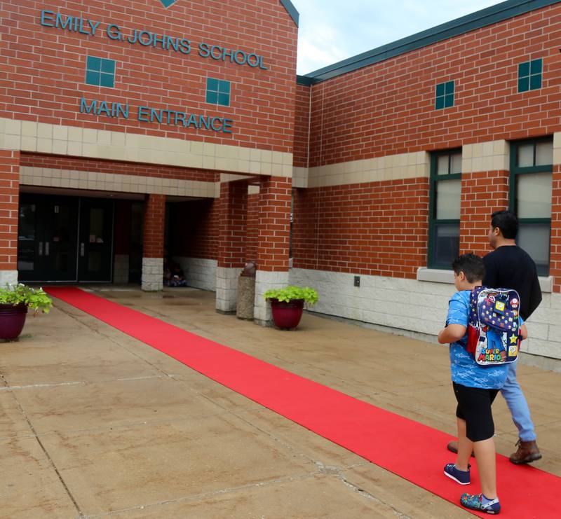 Fifth grader Josias Alvarez walks up the red carpet with his dad, Manny Alvarez, on the first day of school at Emily G. Johns School in Plano on Thursday, Aug. 17, 2023.