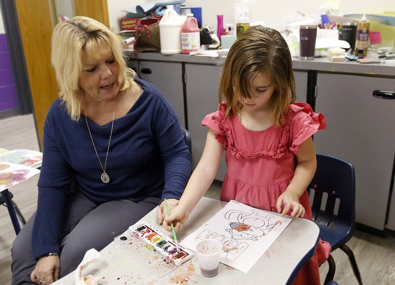 Donna Kus asked questions as Clara Bergman paints the letter M on Thursday, Dec. 14, 2023, during class at the Zion Lutheran Church and School in McHenry.
