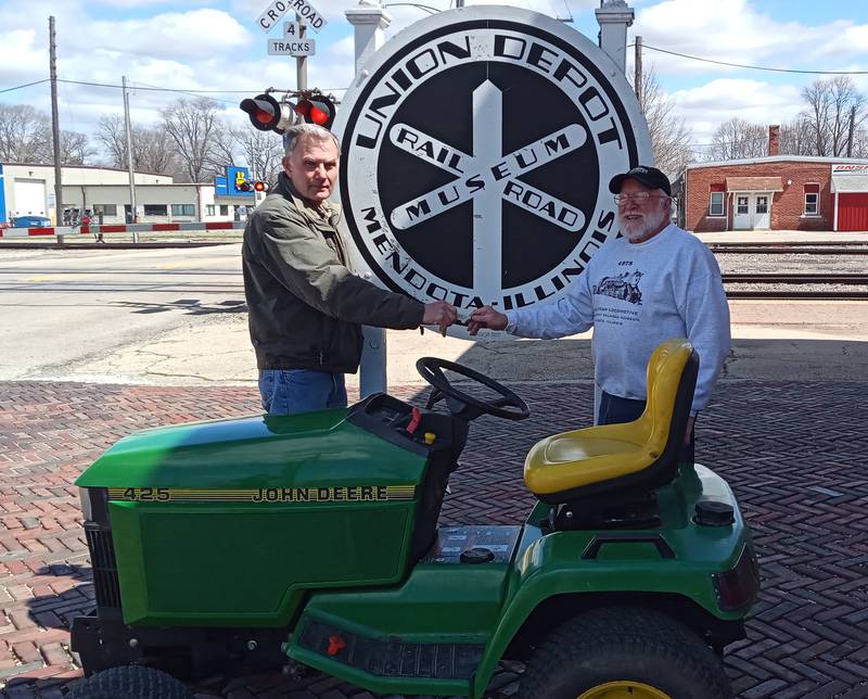 Mendota Museum and Historical Society member Jim Mathesius (left) presents Union Depot Railroad Museum President Allen Russel with the keys to the JD lawn tractor that will be used to power the Union Depot kiddie train for the Mendota Railroad Crossing Day and Country Fair on June 18.