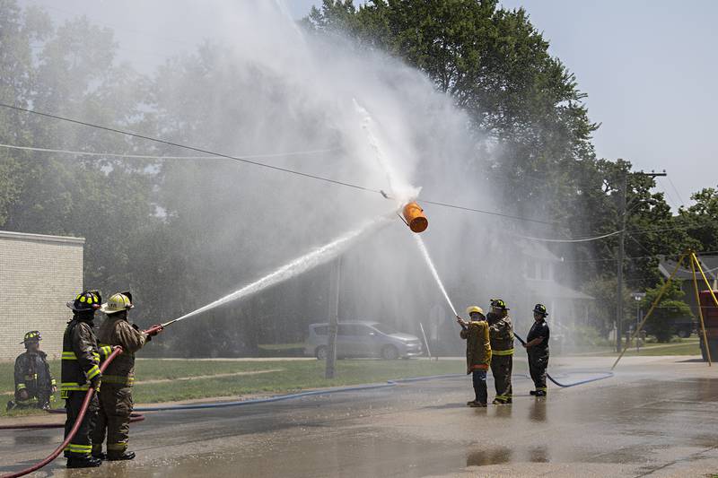 Tampico firefighters concentrate their hoses on a sliding bucket during a water fight Saturday, July 22, 2023 during Tampico Days. The competition pitted firefighter vs firefighter to see who could move the bucket to the opponent’s end zone.