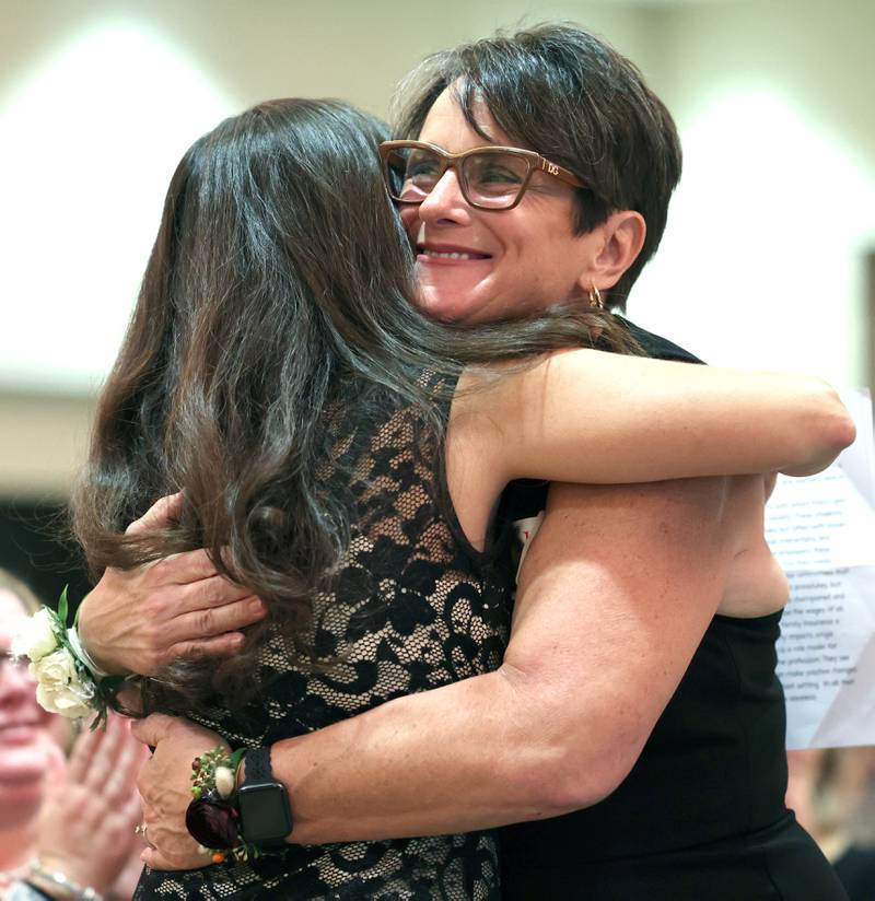 Athena Award finalist Mary Lynn Buckner gets a hug as she comes up to be recognized Tuesday, Oct. 18, 2022, during the Athena and Women of Accomplishment Award reception at the Barsema Alumni and Visitors Center at Northern Illinois University in DeKalb.