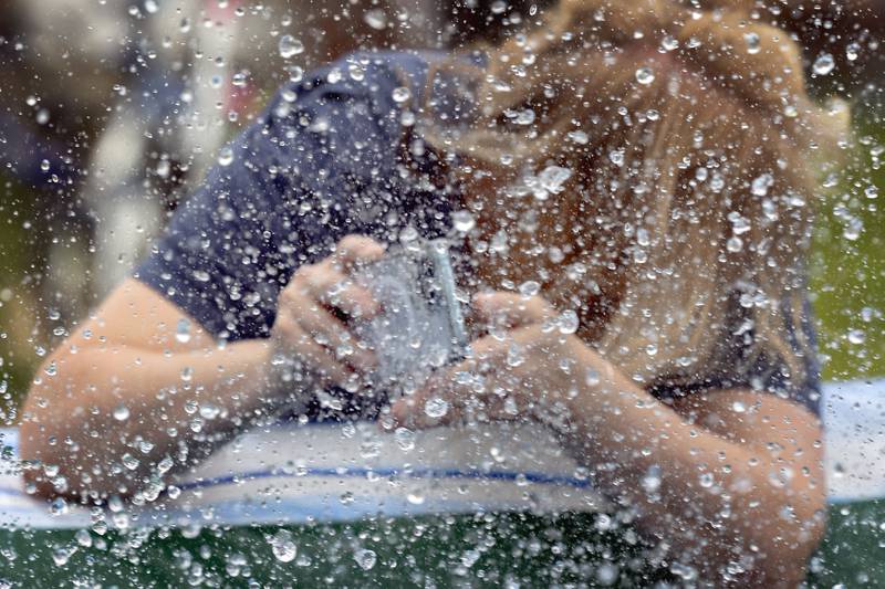 Whiteside County Housing Authority director Jennifer McCleary gets splashed while taking photos of kids on a water slide Friday, Aug. 1, 2025, at the Coloma Township Homes.