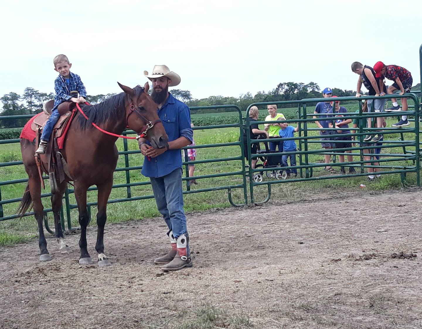 Children look on from outside the horse arena Thursday, July 25, 2022, as Tucker Kehoe rides a horse led by a missionary from Leon River Cowboy Church in Eastland, Texas.