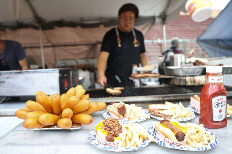 Food options sit on display as a food vendor works the grill at one of the multiple food tents on day 2 of the Taste of Joliet. Saturday, June 25, 2022 in Joliet.