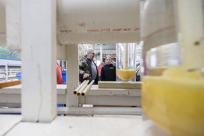 Joe Esposito speaks to students from West Carroll Middle School while gesturing towards jars of walleye eggs Wednesday, April 20, 2023. After harvesting and fertilizing the eggs volunteers wait for the tiny fish to grow a bit before releasing them in a holding pond.