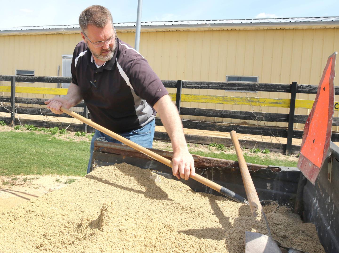 Mark Ekstrom, director of buildings and grounds for Sycamore Community School District 427, rakes dirt into low spots Tuesday, April 11, 2023, in the batting cage behind the softball field at Sycamore High School.
