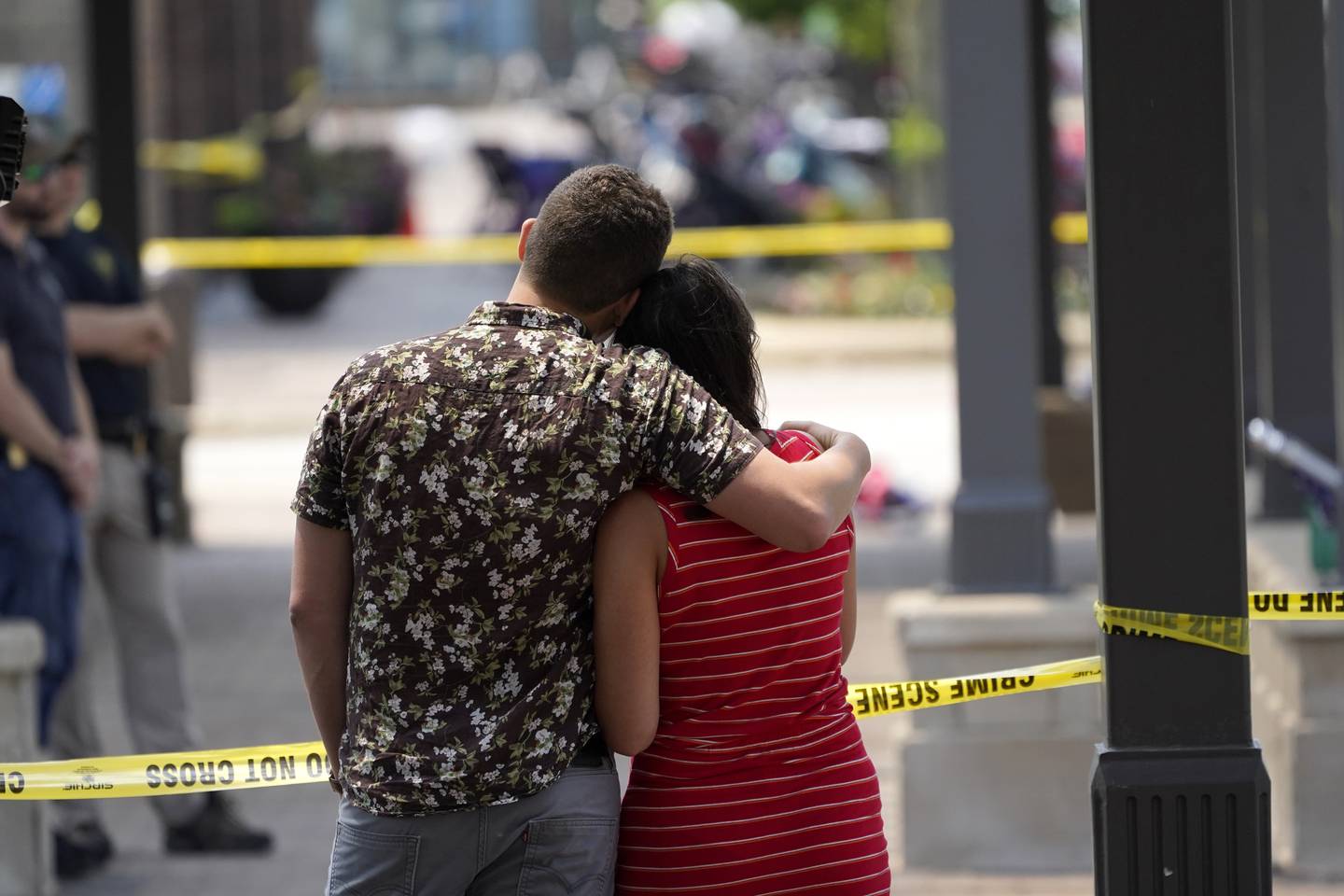 Brooke and Matt Strauss, who were married Sunday, look toward the scene of the mass shooting in downtown Highland Park, Ill., a Chicago suburb, after leaving their wedding bouquets near the scene of Monday's mass shooting, Tuesday, July 5, 2022. (AP Photo/Charles Rex Arbogast)