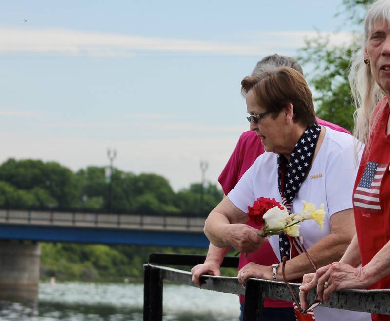 Sue Pearson, in white, tosses a flower into the Rock River in memory of her husband Walter Pearson of the U.S. Army during a Memorial Day observance on Monday, May 29. 2023. To her right, Pearson was in the company of Edna Hurd, who honored Lyle "Whitey" Hemmelman of the Army.