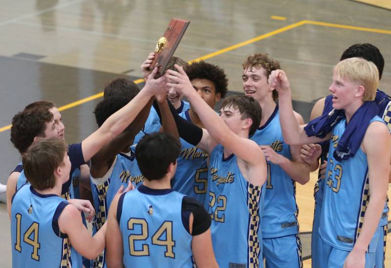 Members of the Marquette boys basketball team hoist the Tri-County Conference Championship plaque on Friday, Jan. 30, 2026 at Putnam County High School.
