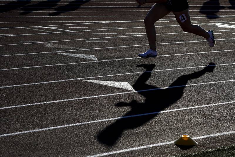 Hampshire’s Alyssa Garcia shadow is cast not eh track as she competes in the 400 meter dash on Thursday, May 8, 2025, during the Fox Valley Conference Girls Track and Field Meet at Huntley High School.