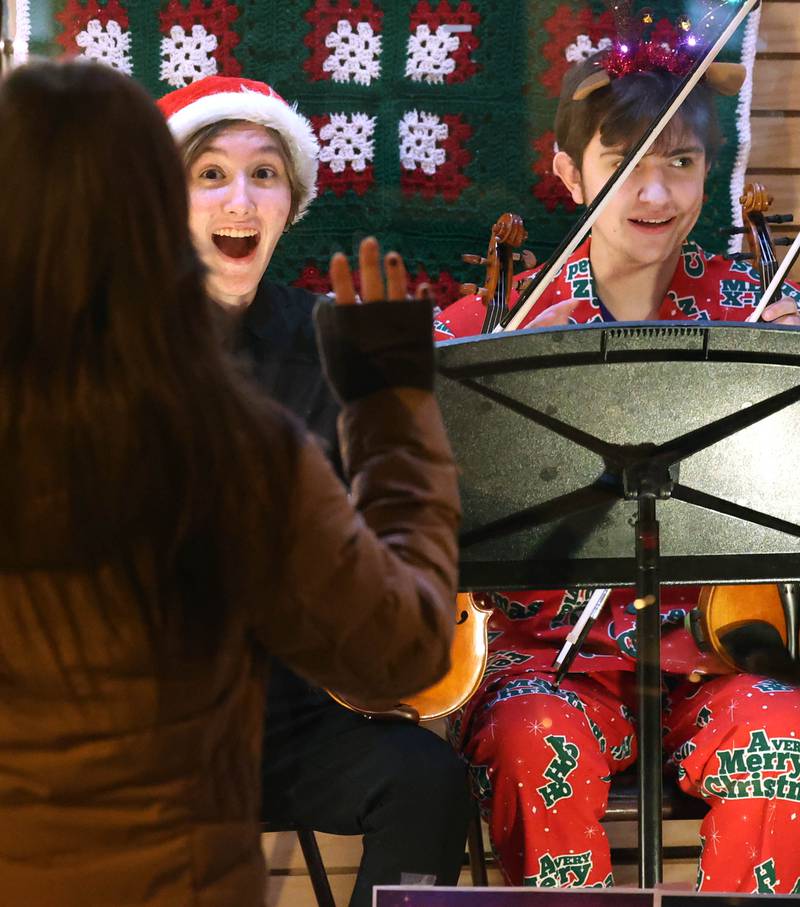 Lillee Torson, (left) and Teagan Tekiela, both sophomores from the Sycamore High School orchestra wave at a friend as they perform in the window of Made Just for You Gifts Friday, Nov. 22, 2024, during Moonlight Magic in downtown Sycamore.