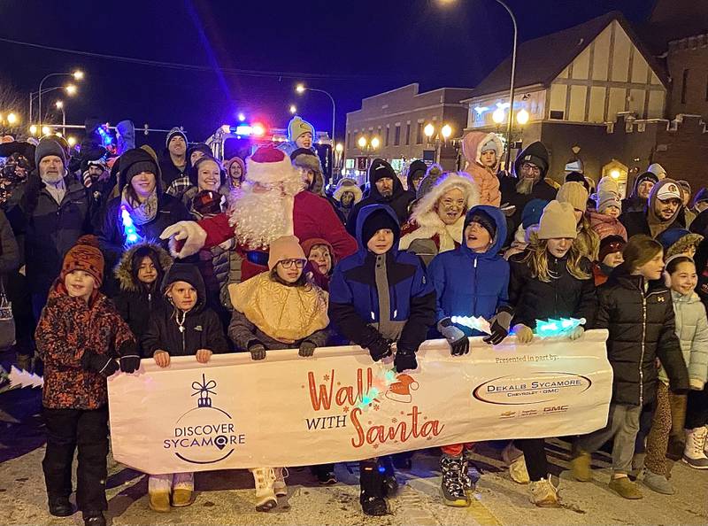 A crowd of children and their families walks with Santa Claus and Mrs. Claus on Friday, Dec. 5, 2025, in downtown Sycamore for the Sycamore Chamber of Commerce's annual Walk with Santa and lighting of the tree.