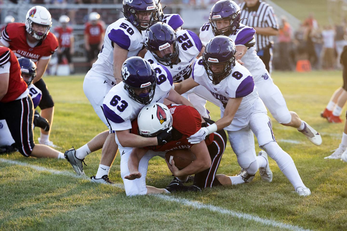Dixon’s Peyton Dingley (63), Aiden Wiseman and Tyson Dambman (8) take down Stillman Valley running back Johnny DeKlerk Friday, August 25, 2023.