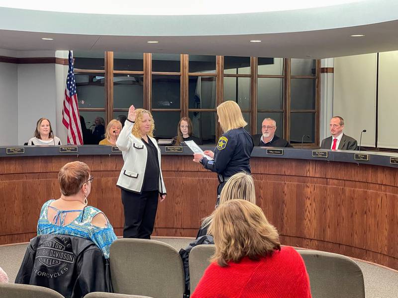 Shannon Andrews, left, is sworn in by Police Chief Mark Frake, right, as Lake in the Hills' new village administrator on Thursday, March 10, 2022.