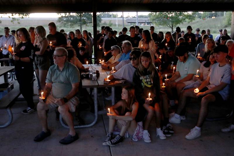 People hold candles during a candlelight celebration for Riely Teuerle on Thursday, August 11, 2022, at Towne Park, 100 Jefferson Street in Algonquin. Teuerle was killed in a car crash in Lake in the Hills on Tuesday. Over 100 family members and friends gathered at the park to remember and celebrate Teuerle’s life.