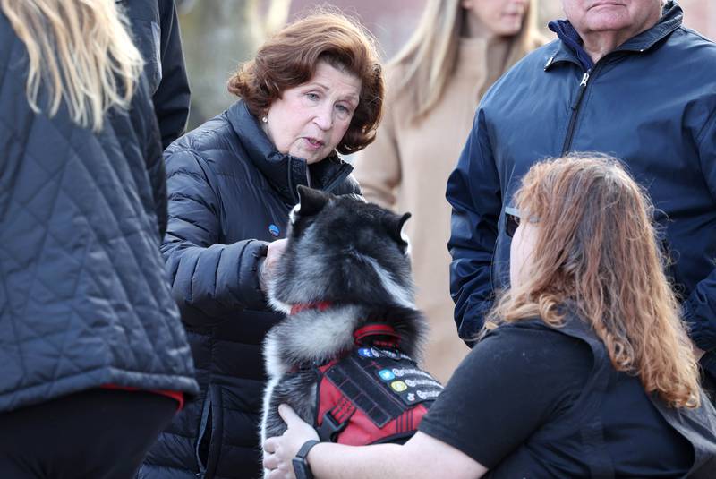 Charlotte Schiller, aunt of shooting victim Julianna Gehant, pets Northern Illinois University Huskie mascot Mission Wednesday, Feb. 14, 2024, during a ceremony in the Peaceful Reflection Garden near Cole Hall at NIU honoring the victims of the 2008 shooting on campus in DeKalb. Wednesday marked 16 years since the deadly shooting took place on campus which took the lives of five people.