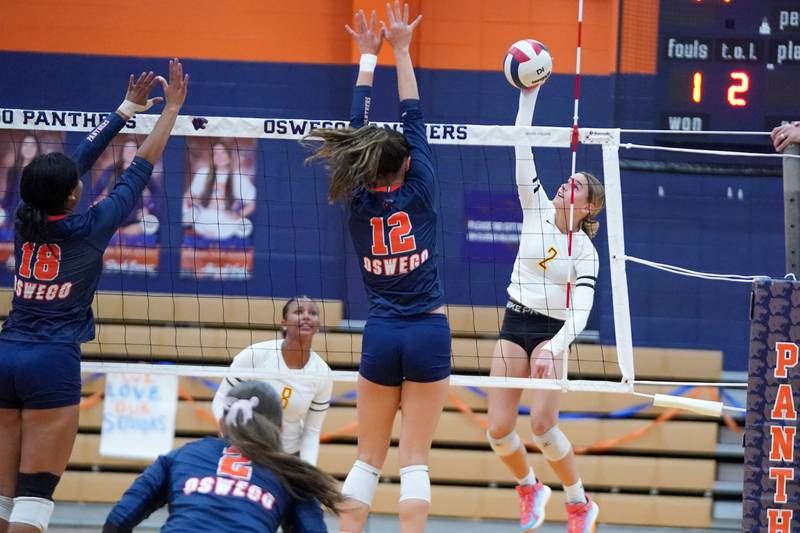 Joliet West's Lexie Grevengoed (2) goes up for a kill attempt against Oswego’s Ava Flanigan (12) and Maya Norlin (18) during a volleyball match at Oswego High School on Thursday, October 24, 2024.