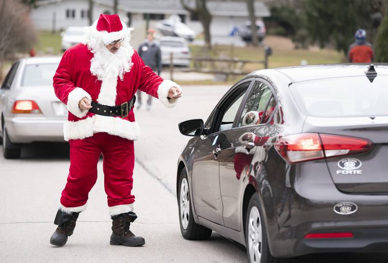 Santa hands out candy to seniors during the second annual drive through Holiday Party in a Bag for local senior adults hosted by the Cary Park District on Thursday, December 23, 2021 at the Cary Community Center. The Holiday Party in a Bag included a holiday meal, small games and treats. Ryan Rayburn for Shaw Local