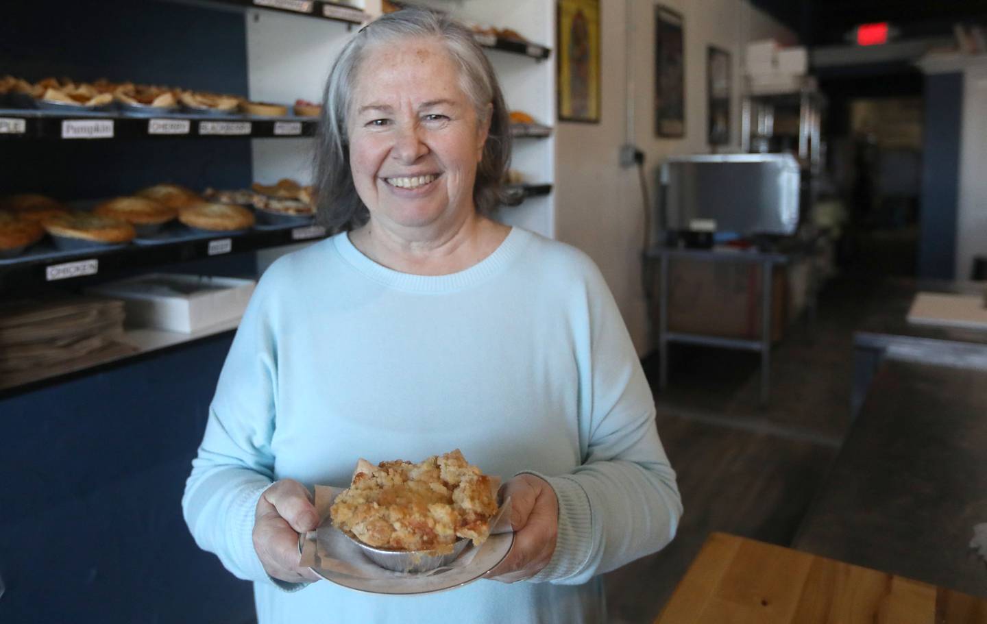 Auriane Ugalde of Pots and Pies Bakery holds an apple pie on Thursday, March 12, 2026, as the bakery prepares for Pi Day on March 14, at the bakery in Crystal Lake.