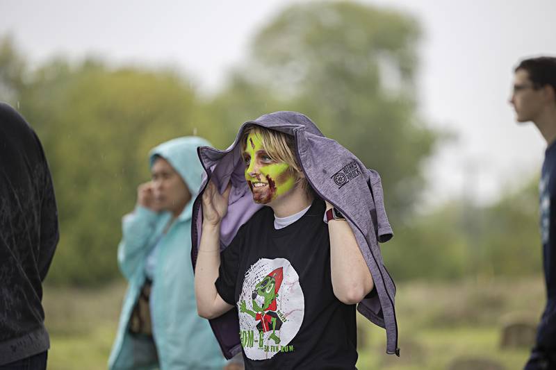 Kyia Cox, shields herself from the rain Saturday, Sept. 16, 2023 before trekking out to scare the runners.