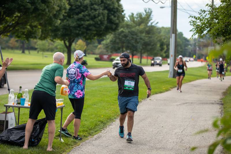 Fox Valley Marathon runners run past the mimosa tent on the trail in St. Charles on Sunday, Sept. 18, 2022.