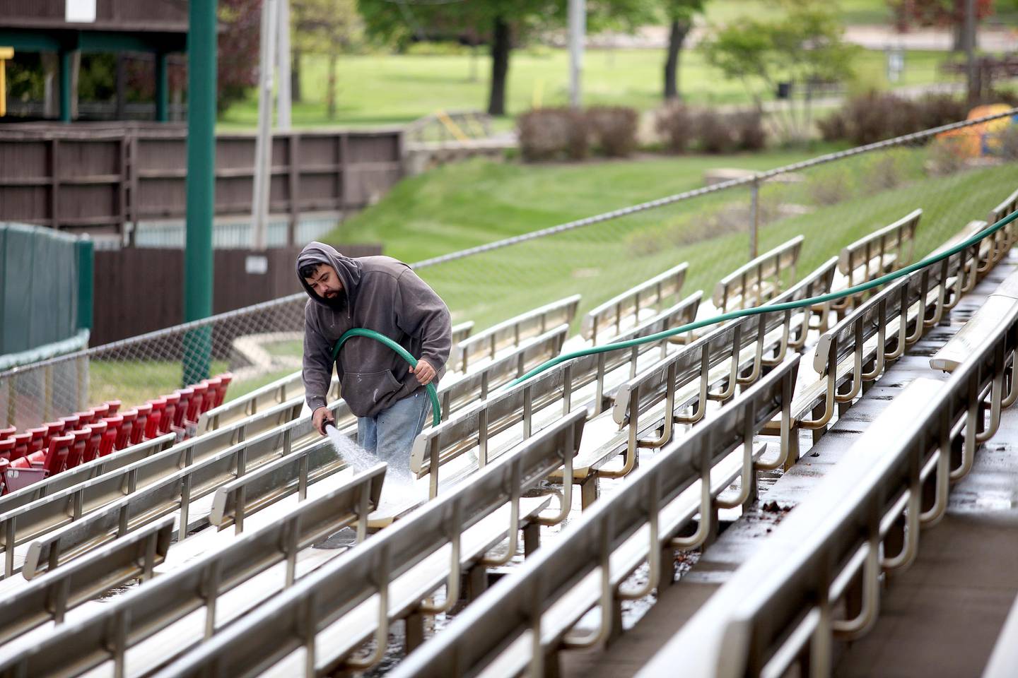 Francisco Amezcua hoses down the seating area at Northwestern Medicine Field in Geneva in preparation for the 2021 Kane County Cougars baseball season.