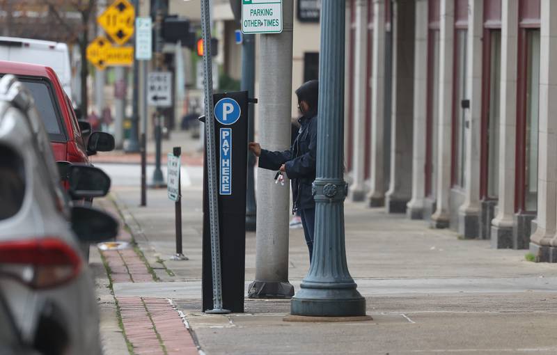 A person pays for parking at a parking kiosk along West Clinton Street in Downtown Joliet on Wednesday, Oct. 25, 2023.
