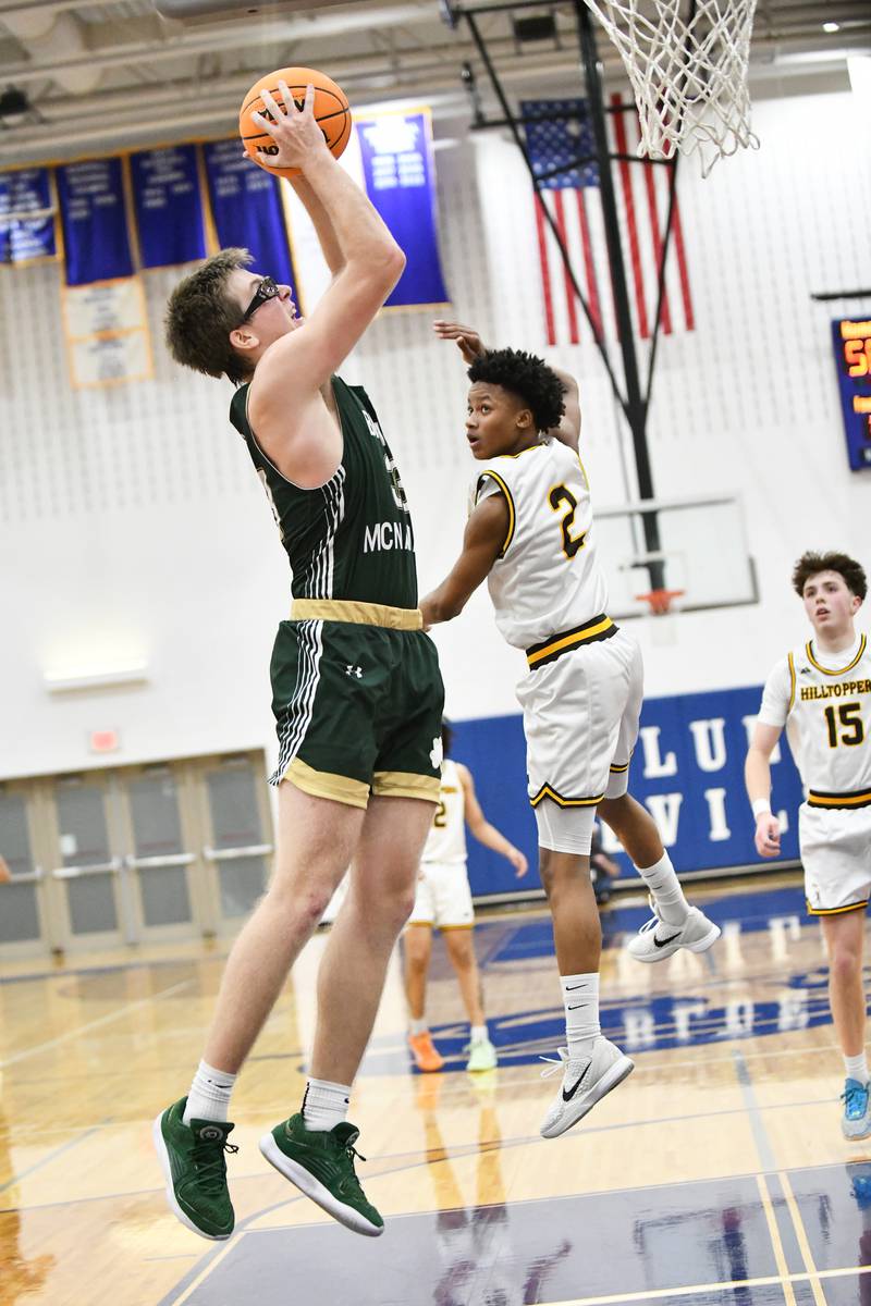 Bishop McNamara's Callaghan O'Connor catches a lob pass over Joliet Catholic Academy's Donavyn Simmons during the Fightin' Irish's 79-67 victory over the Hilltoppers in the IHSA Class 2A Peotone Sectional semifinal on March 4, 2025.