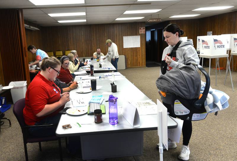 Hannah Hake waits to receive her ballot from Election Judge Dylon Timmer at the Forreston Township Building on Tuesday, Nov. 5, 2024. Hannah's son Bennett, who is two months, tagged along with his mom.
