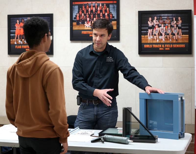 Vince Filicetti, business manager at DeKalb Contract Glazing, talks to an attendee about their products Wednesday, Oct. 22, 2025, during Trades Exploration Day at DeKalb High School. The event hosted several companies and organizations that were offering information on opportunities in the trades.
