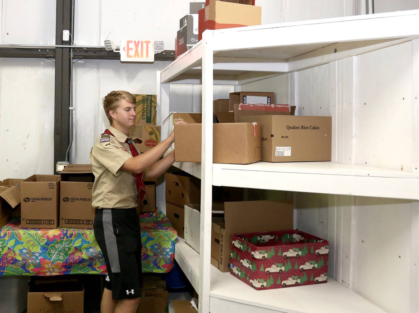Billy Eby arranges boxes on shelves he built as part of his Eagle Scout project at the Between Friends food pantry in Sugar Grove, Wednesday, June 8, 2022.